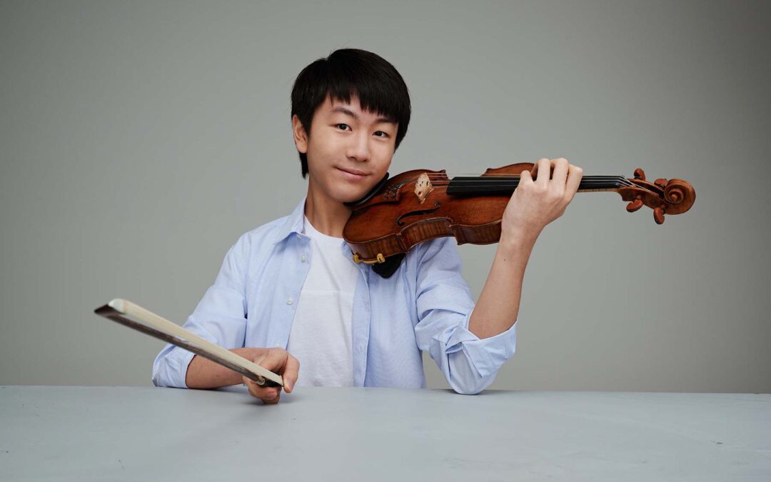 Violinist and conductor Christian Li portrait, holding a violin. Photo by Albert Comper